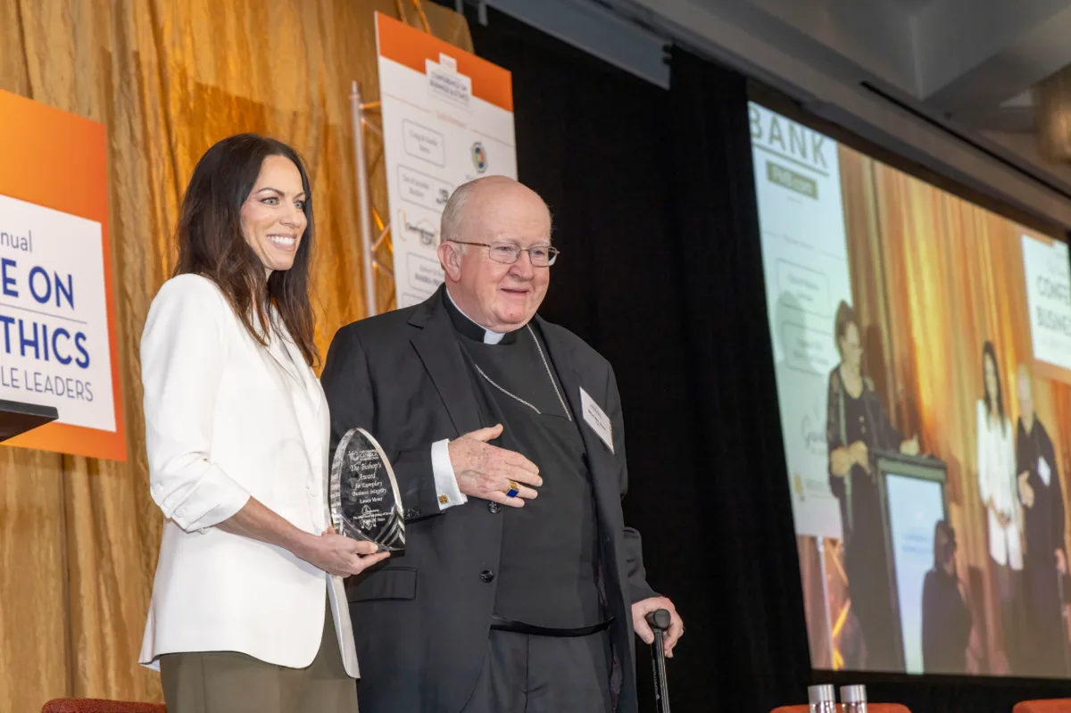 Laura K. Meier, Esq. with Bishop Kevin W. Vann, holding the 2026 Bishop's Award for Exemplary Business Integrity.